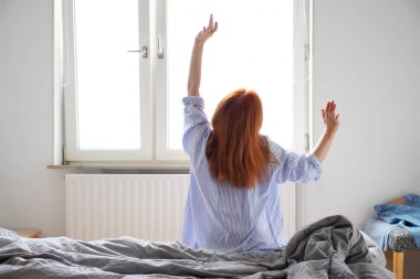 Genç kadın uyandıktan sonra yataktan kalkıyor.