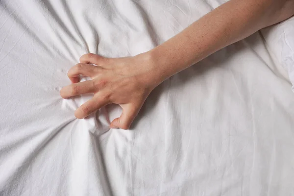Female hand grabs bed sheet — Stock Photo, Image