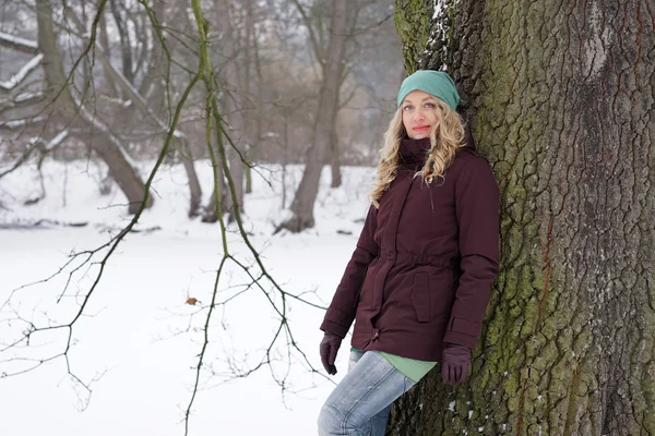 Frau lehnt in Winterlandschaft an Baum — Stockfoto