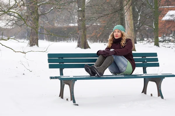 Ensam kvinna som sitter på parkbänken på vintern — Stockfoto