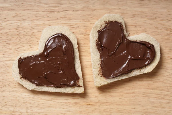 Duas fatias de pão em forma de coração com propagação de chocolate — Fotografia de Stock