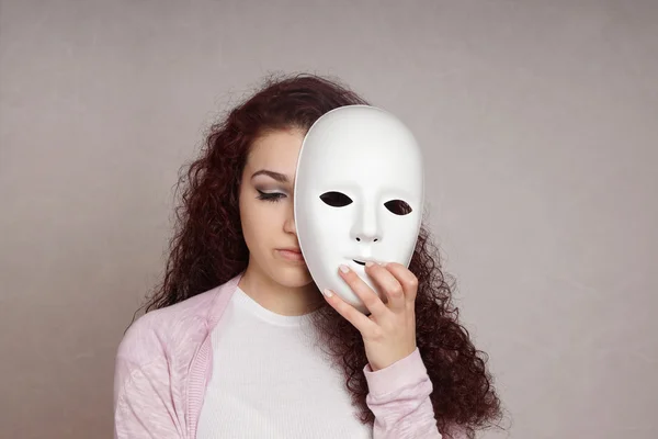 Triste ragazza nascondendo faccia dietro maschera — Foto Stock