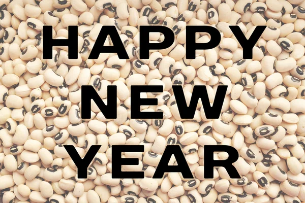 Happy New Year text over black eyes peas — стоковое фото