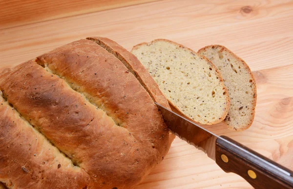 Řezací plátky chleba na dřevěný stůl — Stock fotografie