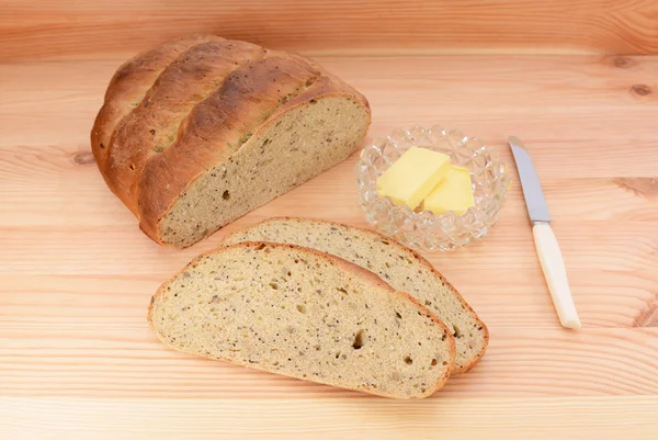 Fresh bread with butter and knife on a wooden table — Stock Photo, Image