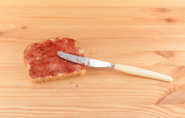 Разбрасывание варенья на свежем хлебе с ножом — стоковое фото
