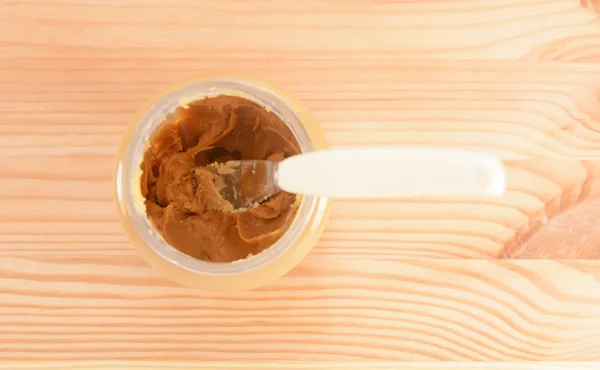 Knife rests in a jar of smooth peanut butter — Stock Photo, Image