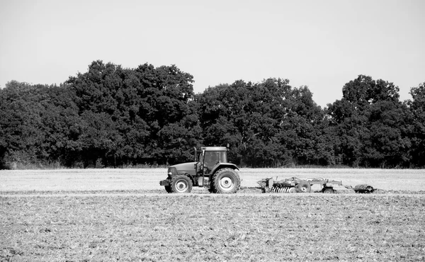Traktor und Egge bearbeiten den Boden — Stockfoto