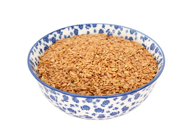 Golden linseed or flax seeds in a blue and white china bowl — Stock Photo, Image