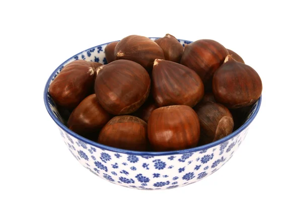 Sweet chestnuts in shells, in a blue and white china bowl — Stock Photo, Image