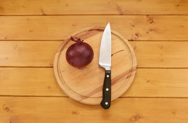 Oignon rouge avec un couteau sur une planche à découper — Photo