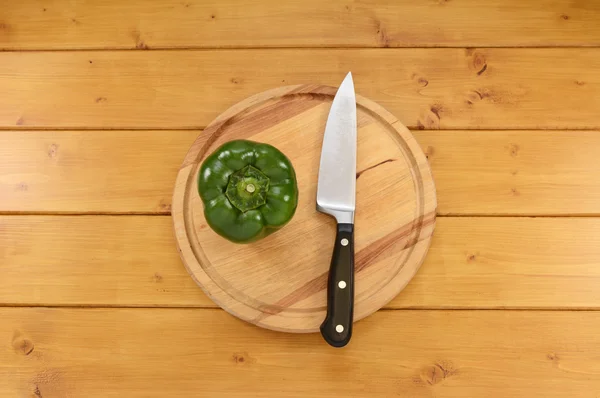 Green pepper with a knife on a cutting board — ストック写真