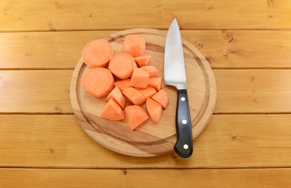 Patata dulce picada con un cuchillo en una tabla de cortar — Foto de Stock
