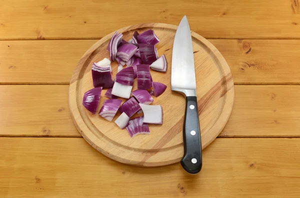 Cebolla roja picada con un cuchillo en una tabla de cortar —  Fotos de Stock