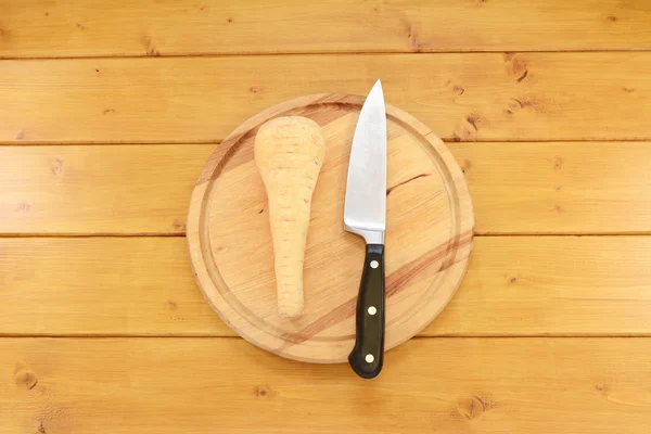 Parsnip cru com uma faca em uma tábua de madeira — Fotografia de Stock