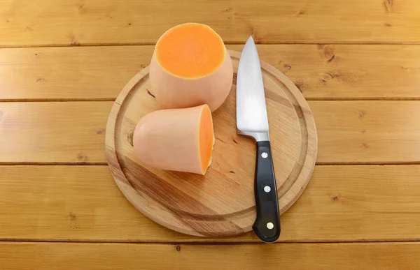 Calabaza cortada por la mitad con un cuchillo en una tabla de madera —  Fotos de Stock