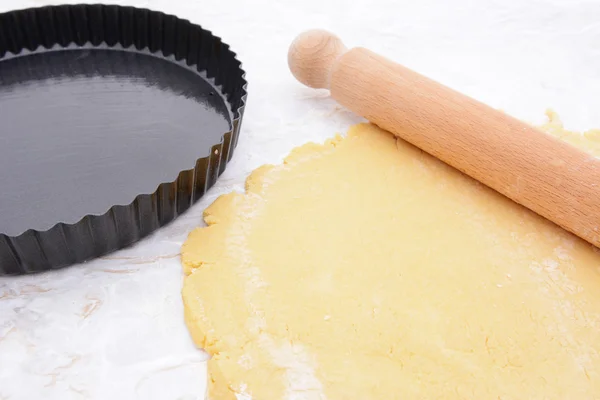 Bakvorm naast caramelstroop gebak en deegroller — Stockfoto