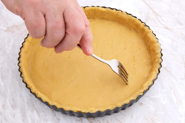 Woman using fork to prick holes in an uncooked pie crust — Stock Photo, Image