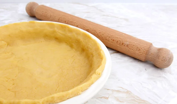 Pie dish lined with pastry with a rolling pin — Stock Photo, Image