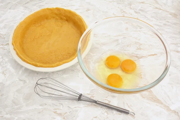 Чашка яиц с венчиком и подкладкой для пирога — стоковое фото