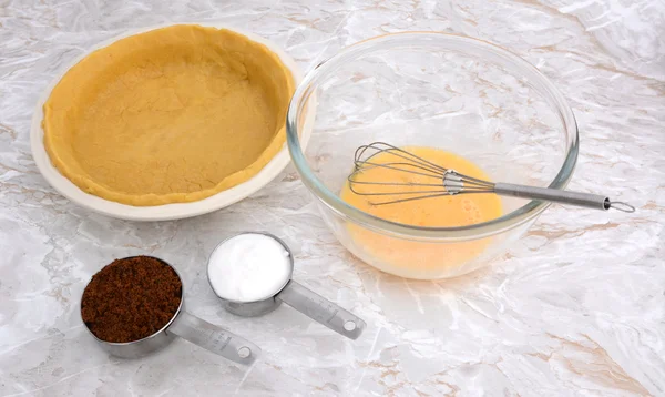 Подкладка блюдо пирога, взбитые яйца и измерительные чашки сахара — стоковое фото