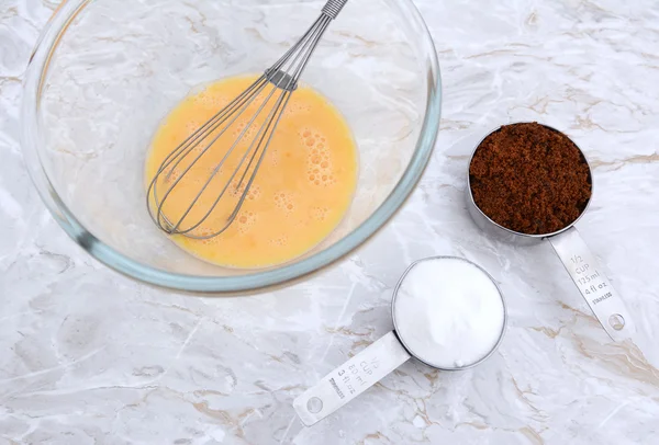 Взбить яйцо венчиком и измерить чашки сахара — стоковое фото