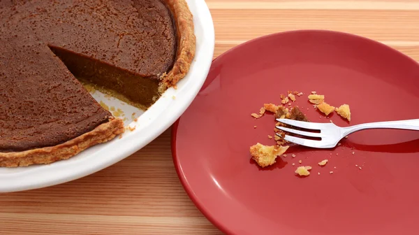 Teller mit Krümeln neben einem aufgeschnittenen Kürbiskuchen — Stockfoto