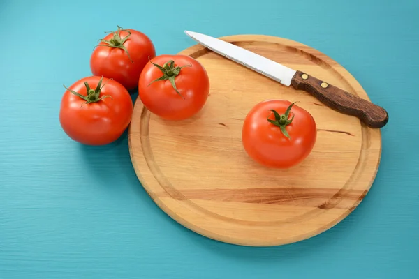 Tomates con un cuchillo dentado en una tabla de madera —  Fotos de Stock