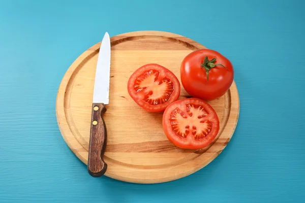 Tomate entero y cortado a la mitad con cuchillo de cocina —  Fotos de Stock