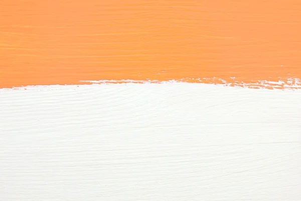 Stripe of orange paint over white wooden background