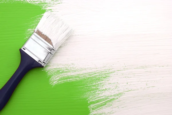 Peinture au pinceau avec peinture blanche sur vert — Photo