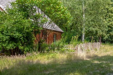 Canlı, ahşap çitleri ve uzun otları olan vahşi bir bahçedeki kır kulübesi geleneksel, basit mimariyi ve doğal, manikürsüz güzelliği sembolize ediyor..