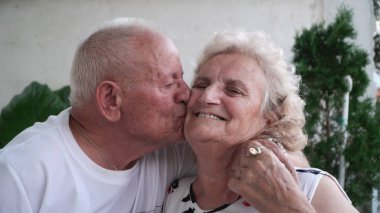 Yaşlı kocayı sevmek, gülümseyen karısını öpmek.