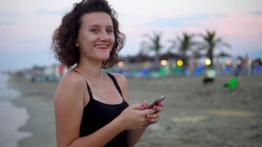 Gün batımında güneşli sahilde dans eden tatlı kız.