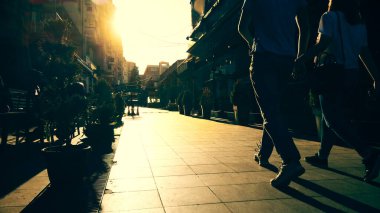 Gün batımında güneşin altında yürüyen bir kızın siluetini izlemek, bir Avrupa şehrinde taş kaldırımda yürümek, mutlu bir yolculuk, Avrupa 'da tatil kavramı.