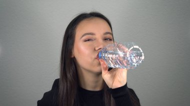 Genç bayan bir şişe su içiyor.