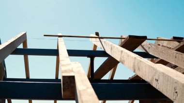 İnşaat işçisi marangoz çatıya çekiçle tahta çakıyor.