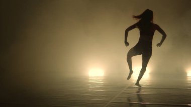 Dansçı kadın, karanlık ışıklı odada gösteri yapıyor.