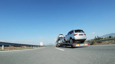 Büyük bir kamyon / araba taşıyıcısı otoyolda kullanılmış araba dağıtıyor.