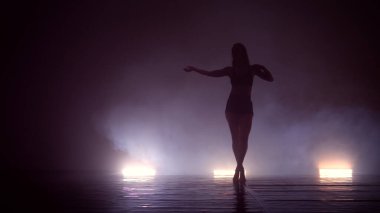 Dans eden, karanlık dumanlı stüdyoda eğitim gören genç bir kadının silueti. Sokak hip hop dansçısı. Spor salonunda egzersiz.