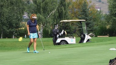 Bansko, Bulgaristan - 20 Ağustos 2019: Kadın golfçü atışı kaçırmadan önce çömeldi ve yeşili inceledi