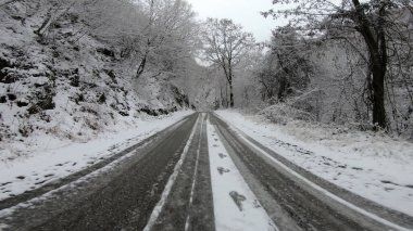 Genç sağlıklı sporcu karlı dağ yolunda asfalt yolda koşuyor.