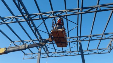 Rigger yüksek kiraz toplayıcıda. İnşaat alanının üzerinden geçiyor.