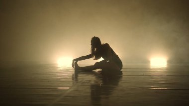 Dansçı kadın, karanlık ışıklı odada gösteri yapıyor.