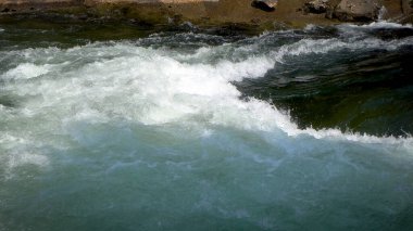Dağ nehri kayaların arasında hızla akıyor, rafting için mükemmel. 