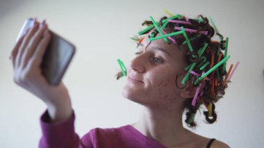 Plastik pipetten yapılmış saçı olan heyecanlı İspanyol kadın selfie çekiyor.