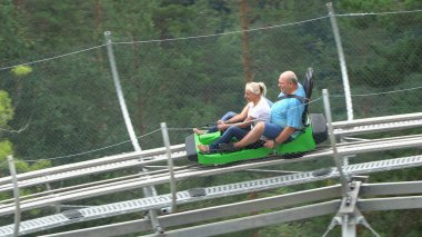 Bansko, Bulgaristan - 20 Ağustos 2019: Erkek ve kız yaz eğlence treni yolculuğunun tadını çıkarıyorlar. Kırmızı bir lunaparkta heyecanlı bir yolculuktan zevk alırken komik bir ifadeleri vardır.