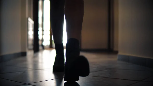 遅い動きで廊下に沿って実行されているブーツの女性の足のシルエットの低セクションとSteadicam — ストック写真