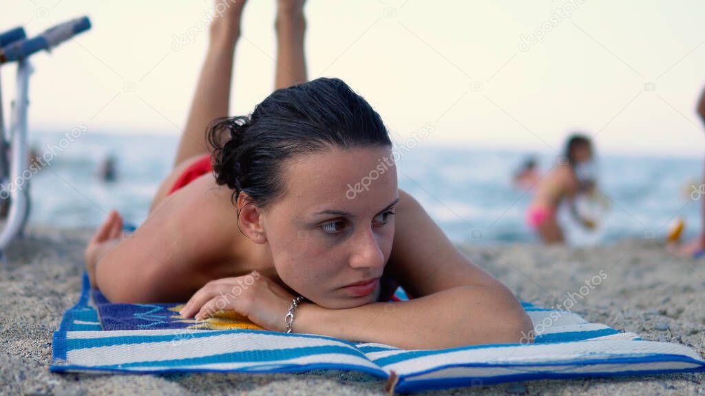 Beautiful teen girl with freackles enjoying on the sand on a full beach with unrecognizable people