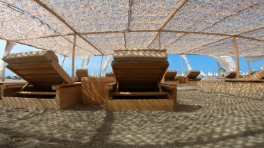 Lüks tatil beldesi kumlu bir plajda, mavi güneşli gökyüzünün arka planında beyaz çadır.